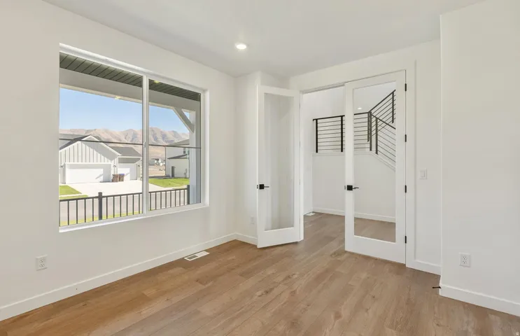 Unfurnished bedroom featuring french doors, light wood finished floors, a mountain view, and recessed lighting
