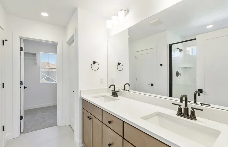 Full bathroom featuring double vanity, a shower stall, and recessed lighting