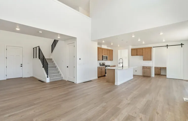 Kitchen featuring a barn door, open floor plan, recessed lighting, a center island with sink, and stainless steel appliances