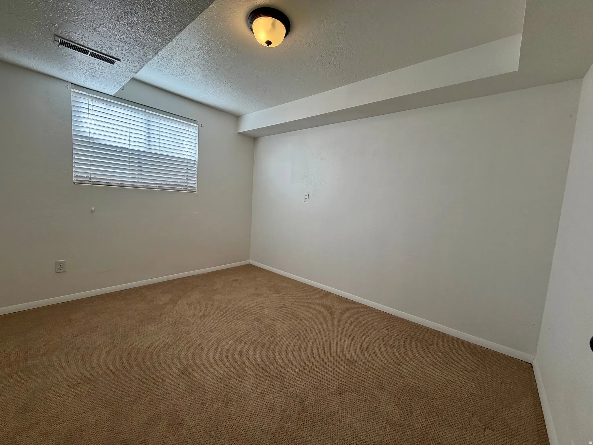 Empty room featuring carpet flooring and a textured ceiling