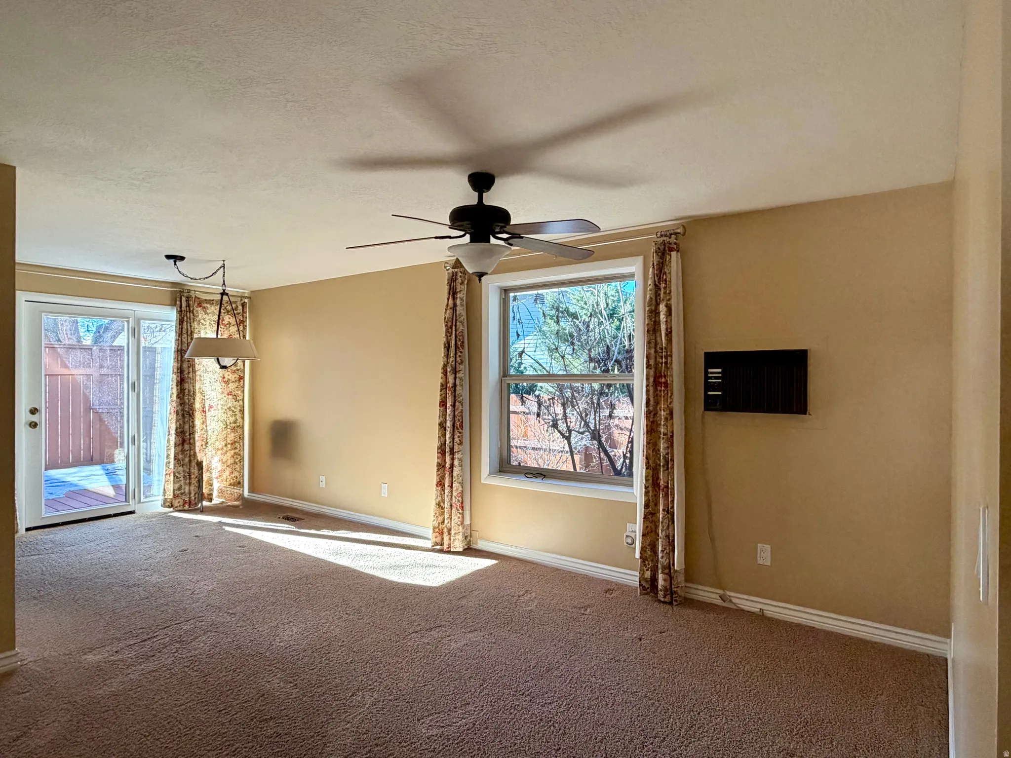 Carpeted empty room featuring a ceiling fan and a textured ceiling
