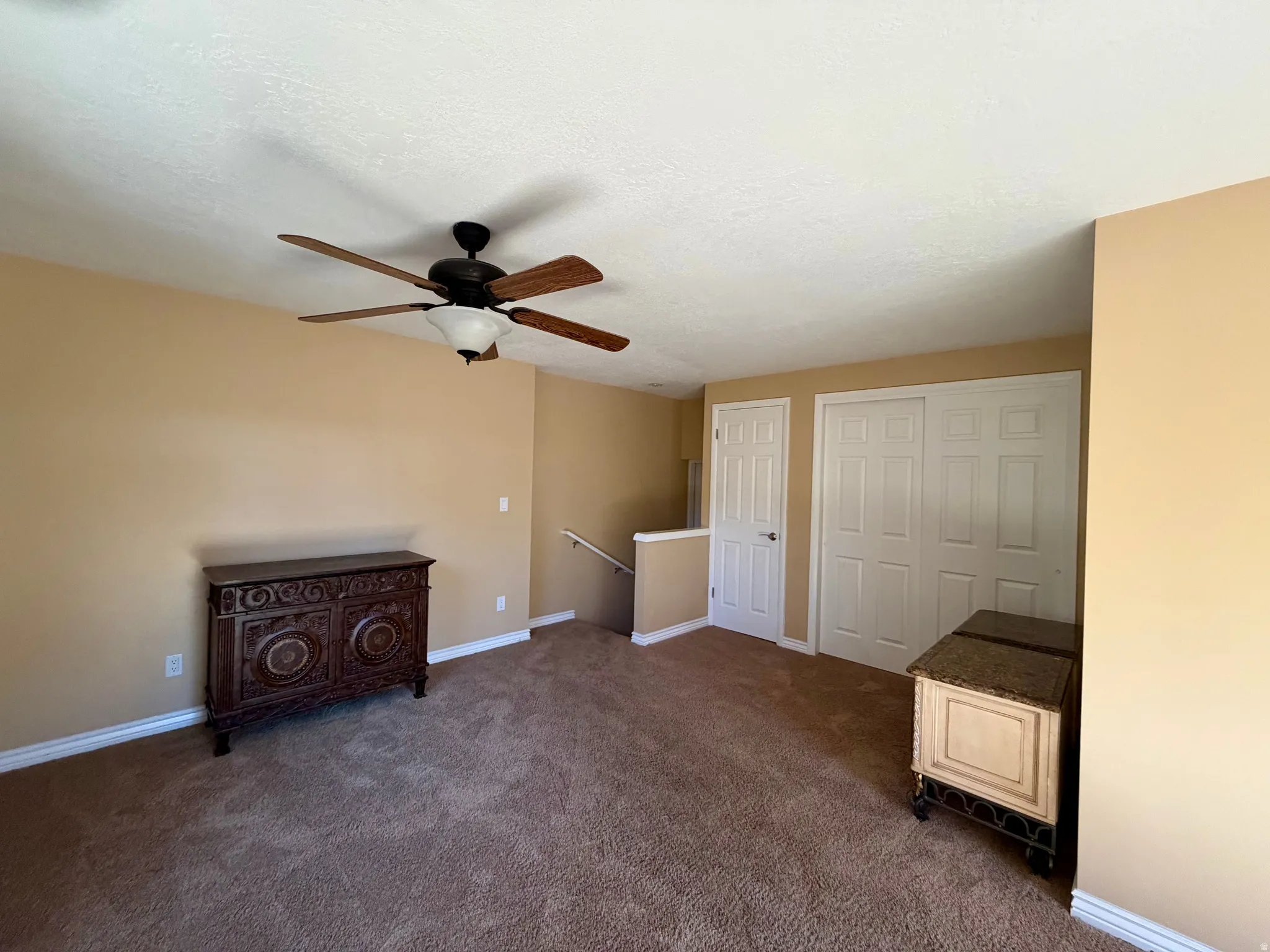 Unfurnished bedroom with a closet, dark carpet, and a ceiling fan