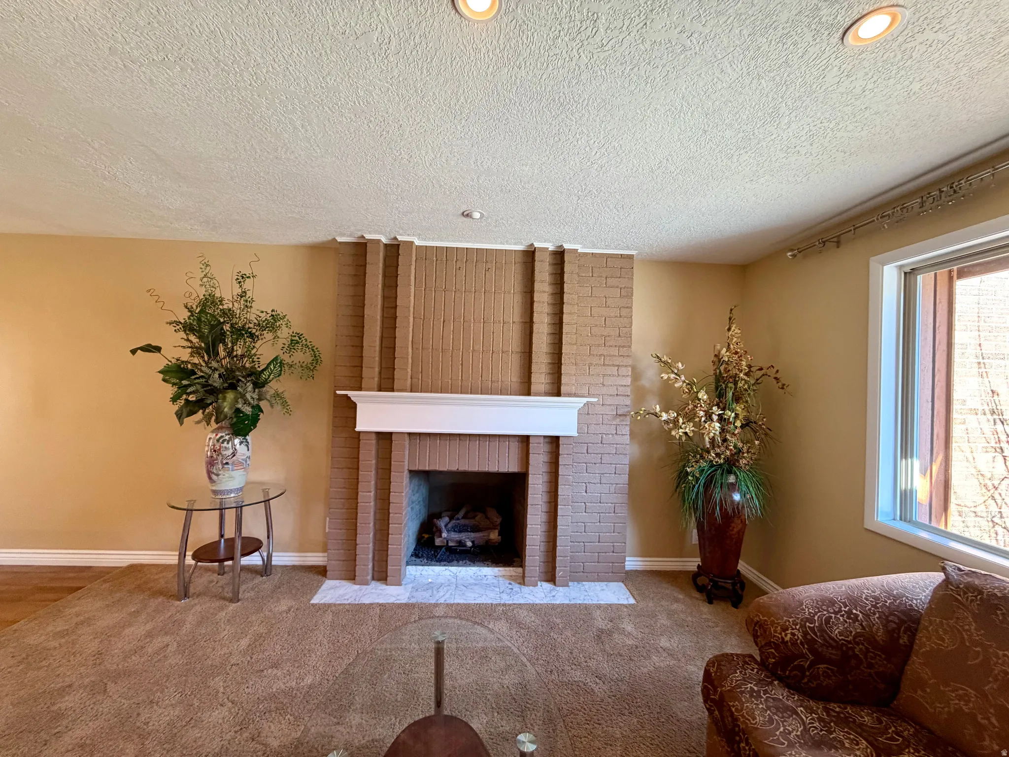 Carpeted living area featuring a fireplace, a textured ceiling, and recessed lighting