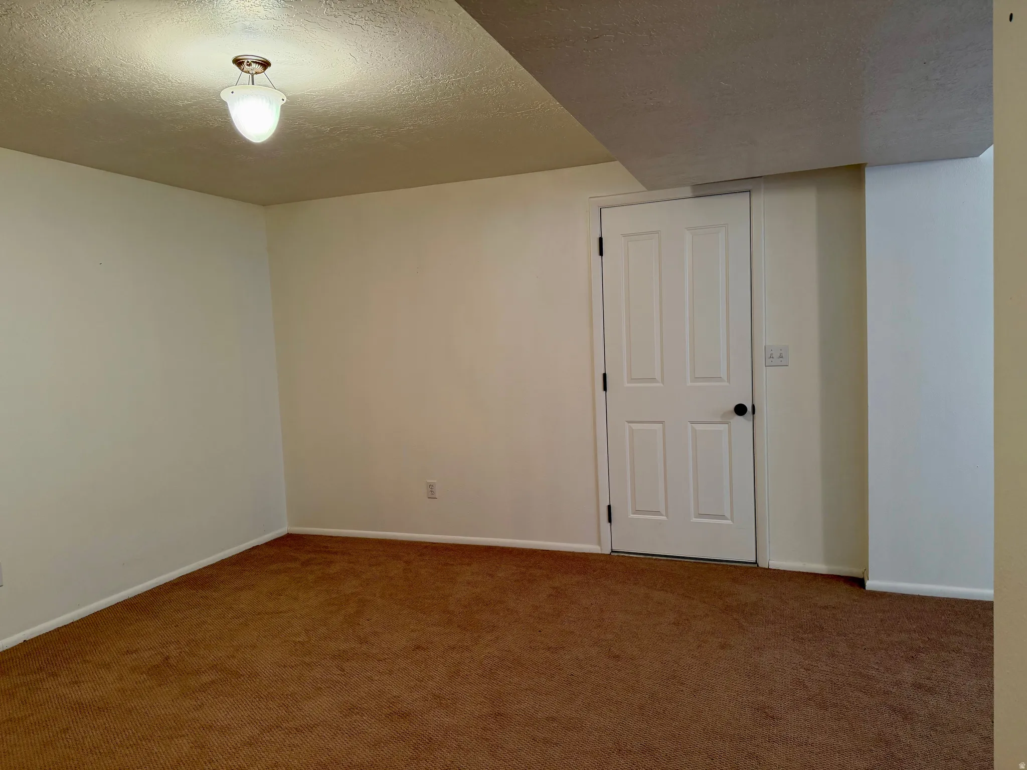 Carpeted spare room with a textured ceiling and baseboards