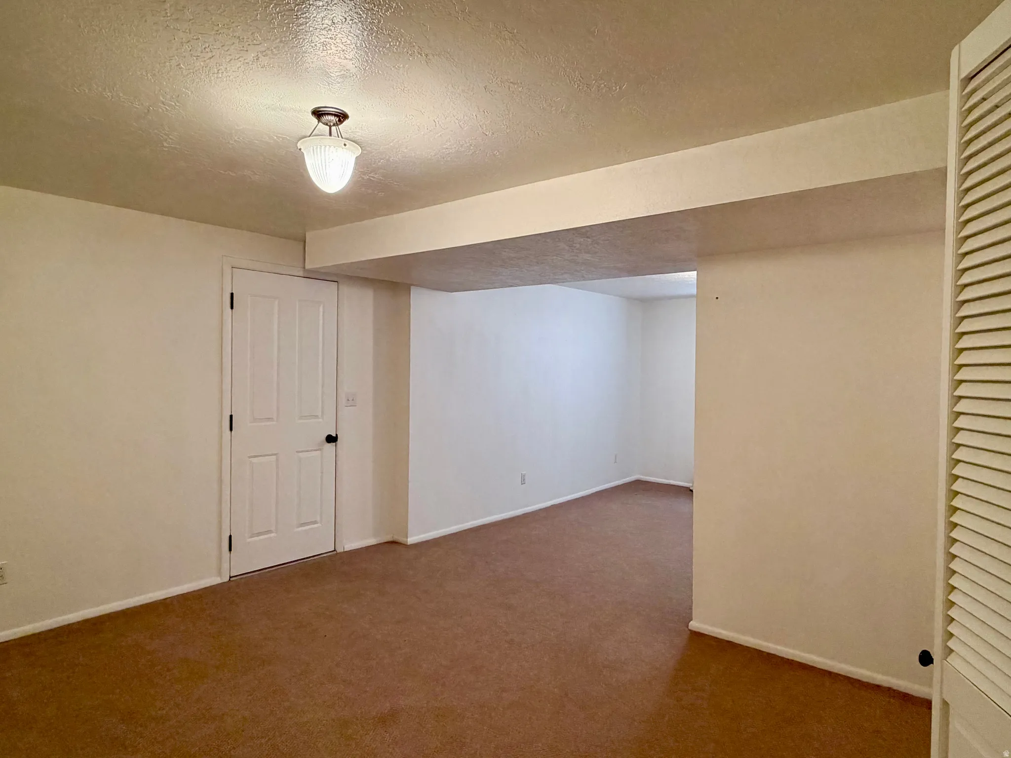 Finished below grade area with a textured ceiling and carpet floors