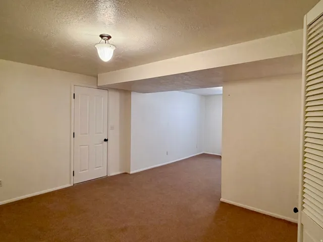 Finished below grade area with a textured ceiling and carpet floors