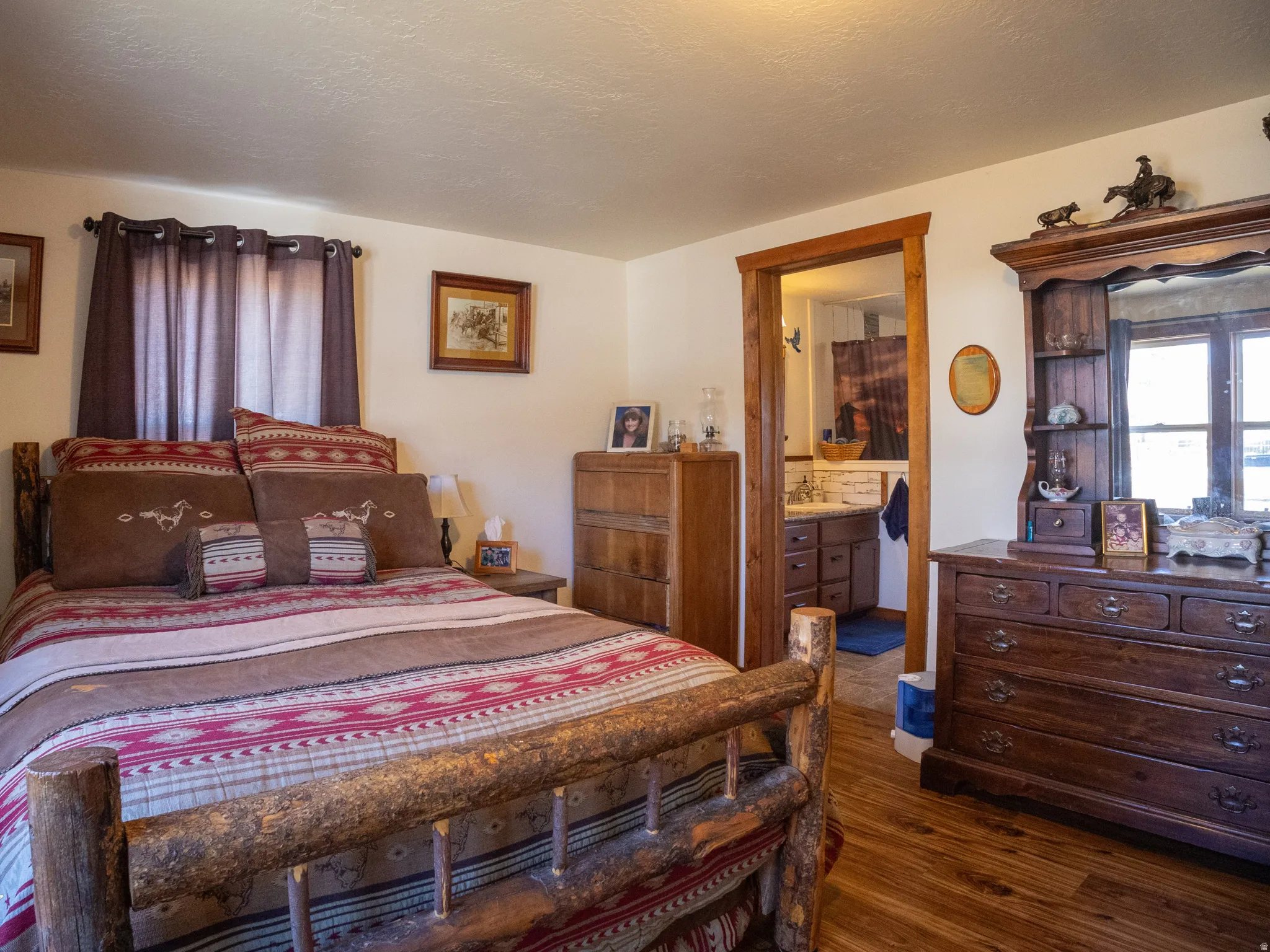 Bedroom with dark wood-style flooring, ensuite bath, and a textured ceiling