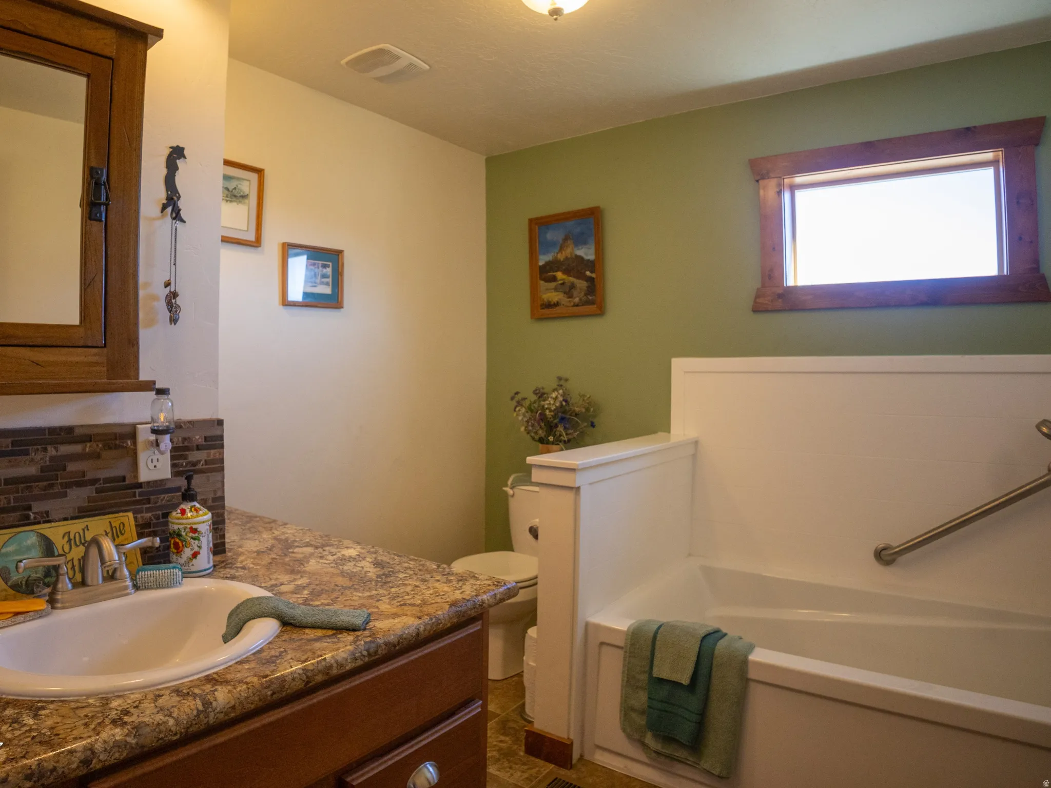 Bathroom with vanity, a garden tub, and tasteful backsplash