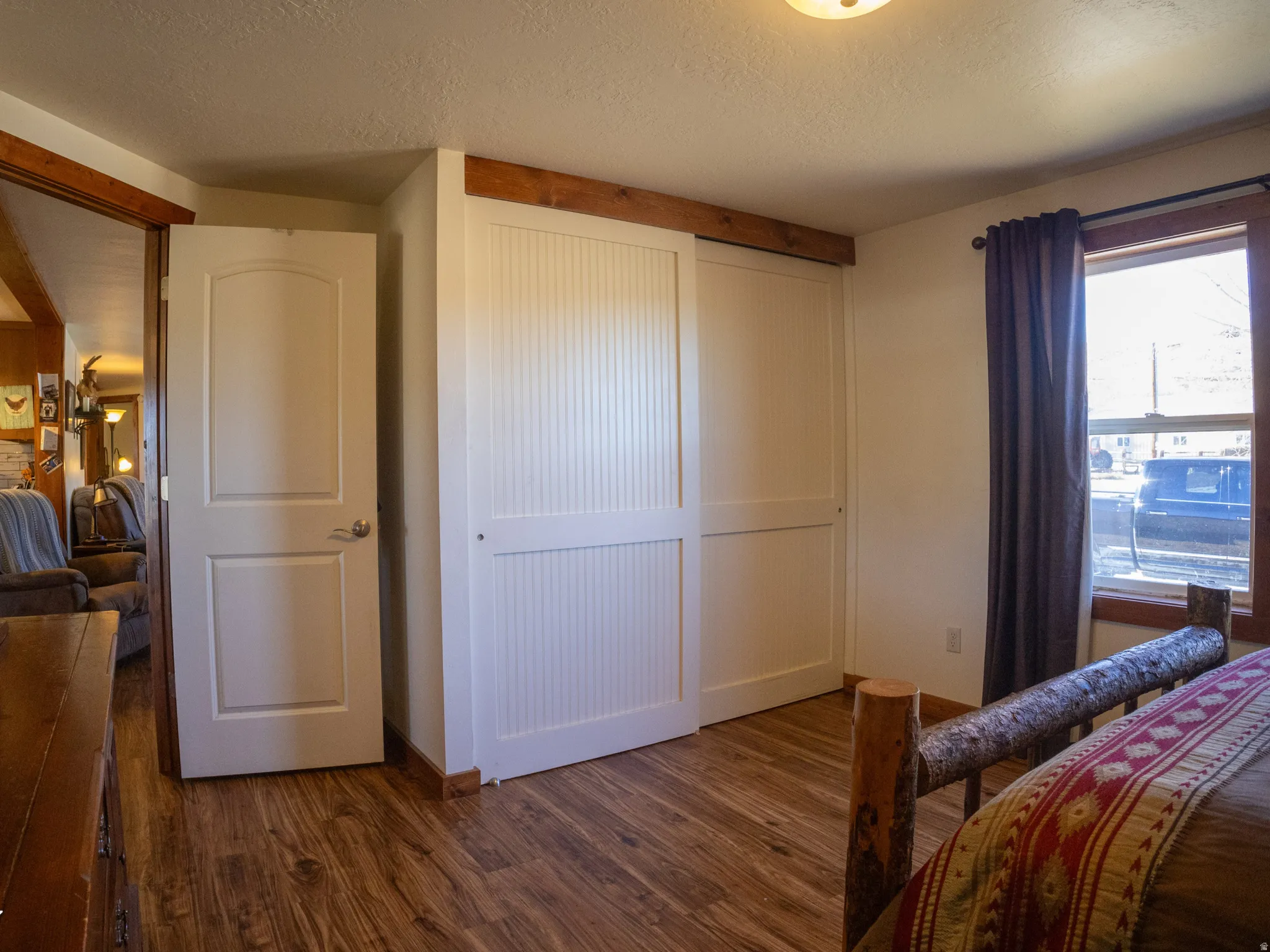 Bedroom with a textured ceiling, dark wood-style flooring, and a closet