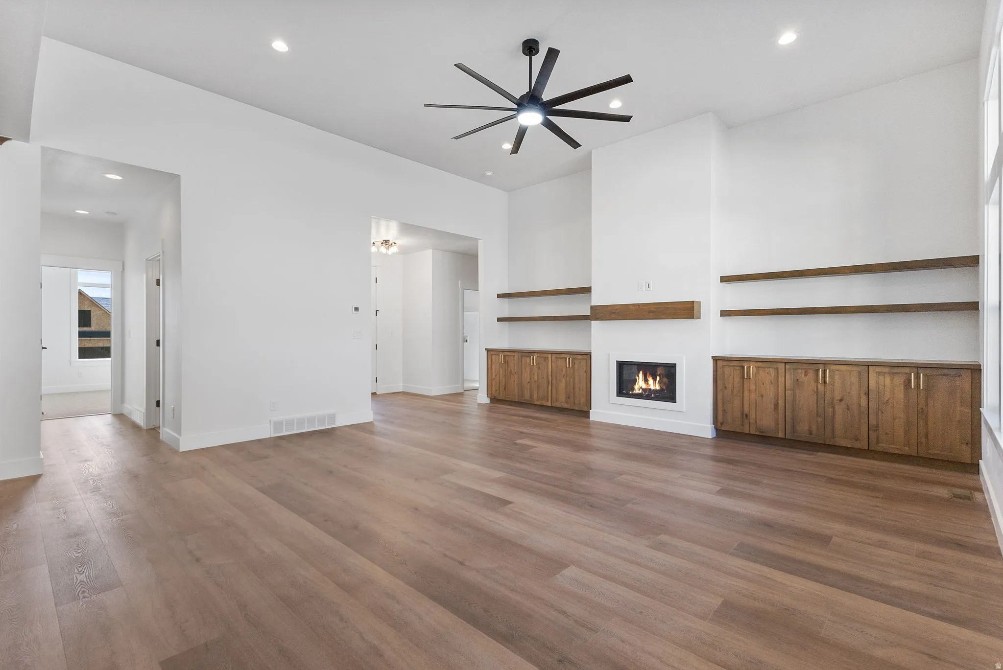 Unfurnished living room with a glass covered fireplace, recessed lighting, wood finished floors, and a ceiling fan