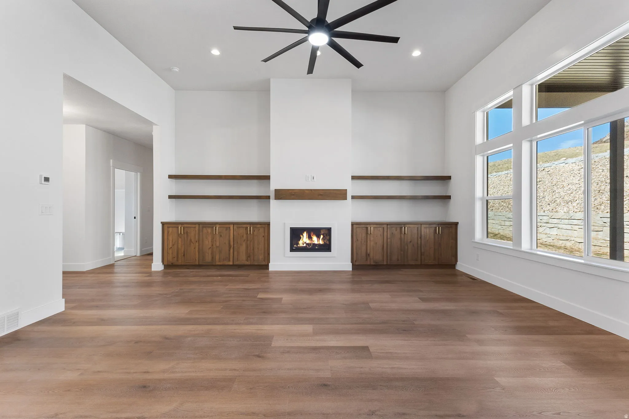 Unfurnished living room with a glass covered fireplace, dark wood-style floors, recessed lighting, and a ceiling fan