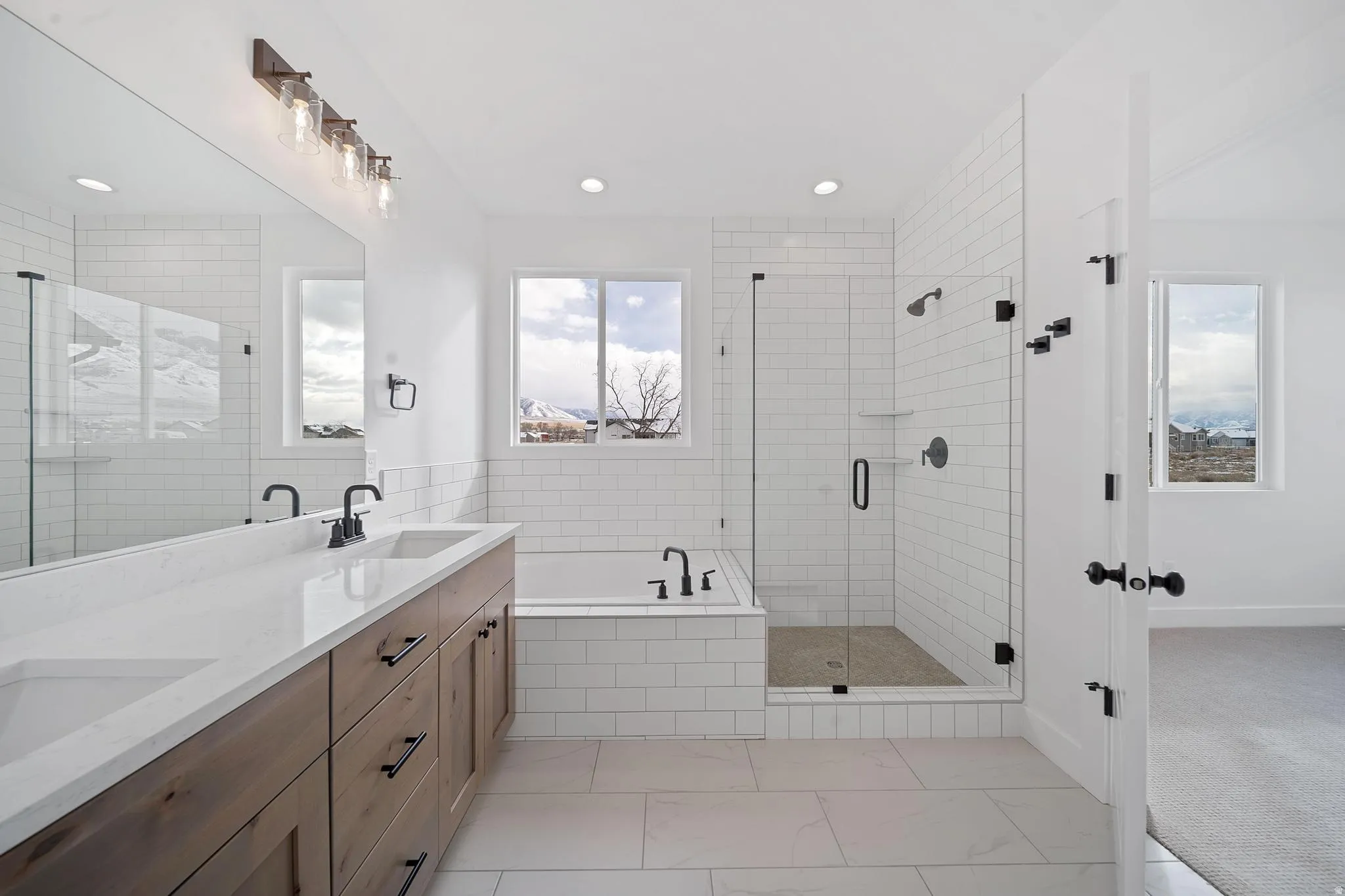 Full bathroom with double vanity, a garden tub, a stall shower, and light marble finish floors