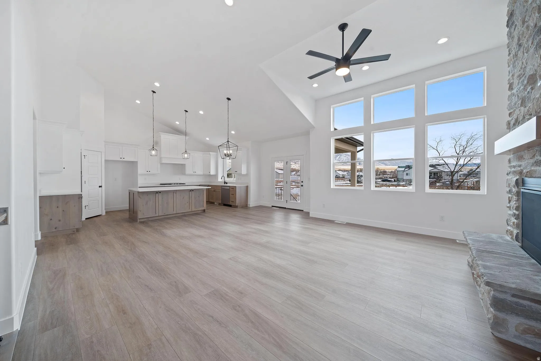 Unfurnished living room with a towering ceiling, light wood-style flooring, a fireplace, a ceiling fan, and recessed lighting