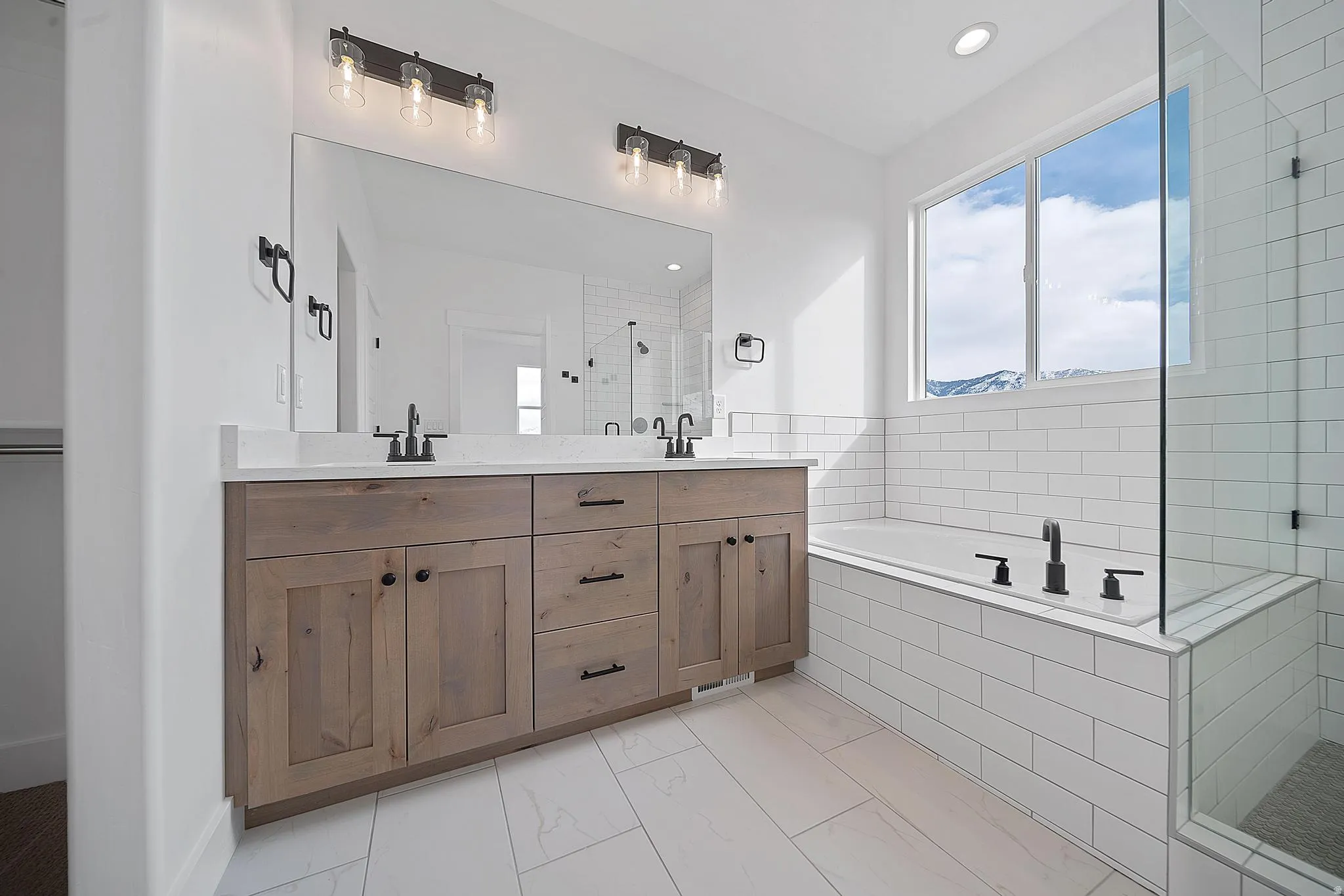 Full bathroom with double vanity, a bath, a shower stall, and light marble finish floors