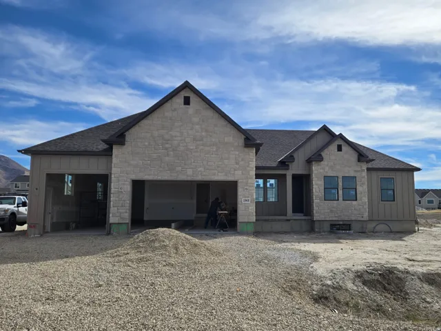 View of front facade featuring board and batten siding, driveway, roof with shingles, and an attached garage