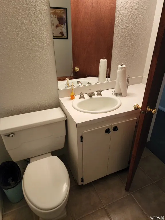Bathroom featuring a textured wall, vanity, and dark tile patterned flooring