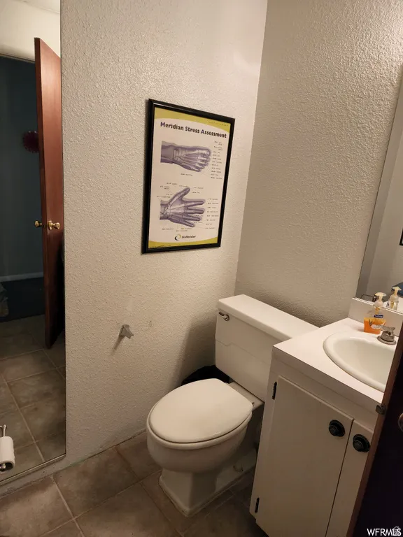 Half bath with a textured wall, vanity, and tile patterned flooring