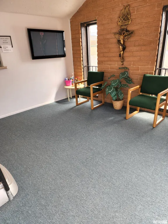 Living area featuring lofted ceiling and brick wall
