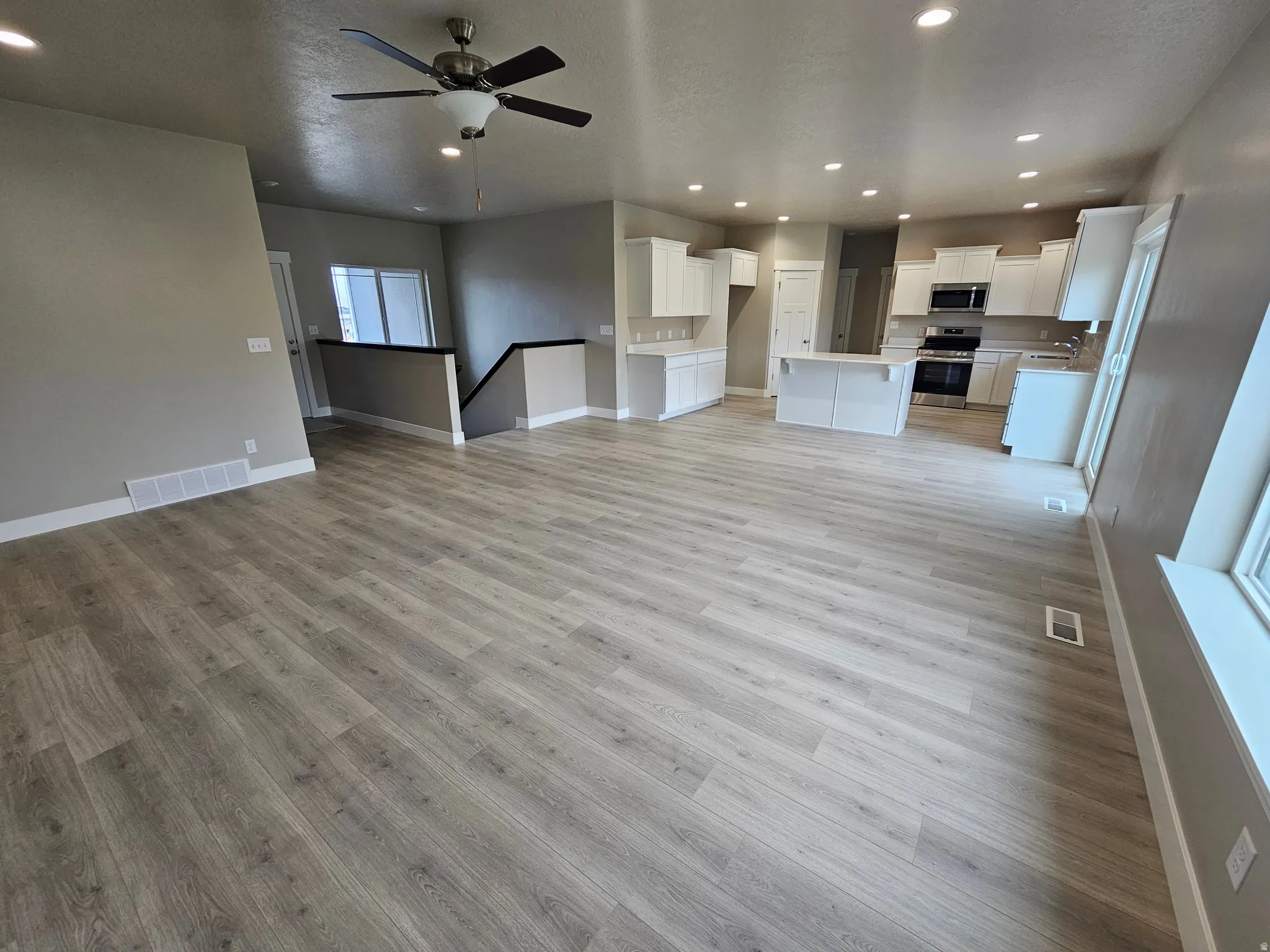 Unfurnished living room with recessed lighting, light wood finished floors, ceiling fan, and a textured ceiling