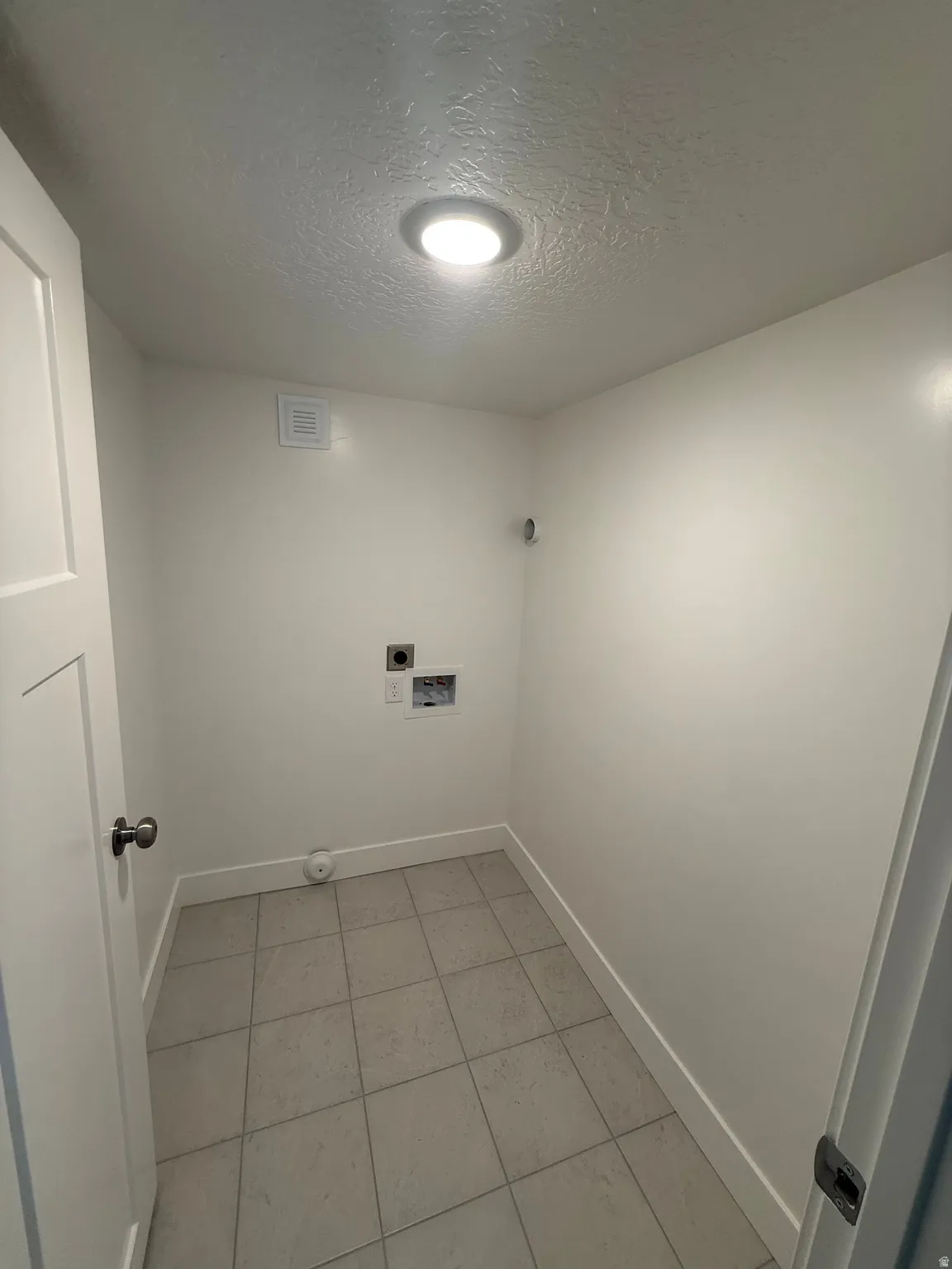 Laundry room with a textured ceiling, light tile patterned flooring, electric dryer hookup, and hookup for a washing machine