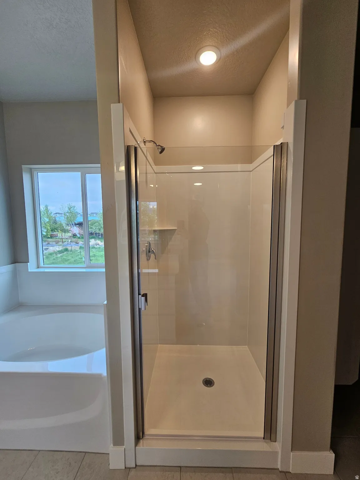 Bathroom with a shower stall, tile patterned flooring, a textured ceiling, and a bath