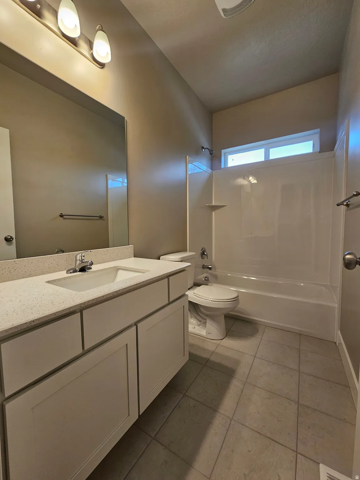 Bathroom featuring shower / washtub combination, vanity, and light tile patterned floors