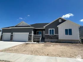 View of front of house with an attached garage, driveway, board and batten siding, and stone siding