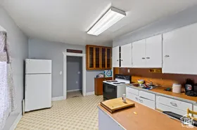 Kitchen featuring white cabinets, freestanding refrigerator, light countertops, electric range oven, and glass insert cabinets