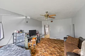 Carpeted bedroom with a textured ceiling and ceiling fan