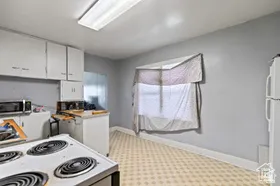 Kitchen featuring white cabinetry, white appliances, and light countertops