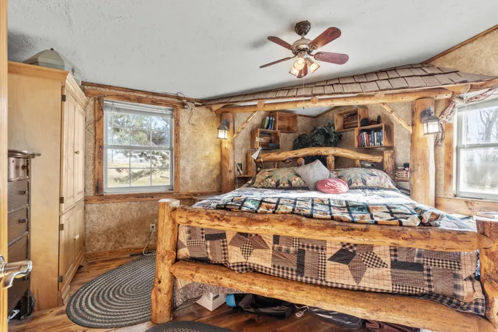 Bedroom featuring wood finished floors, vaulted ceiling, a textured ceiling, and a ceiling fan