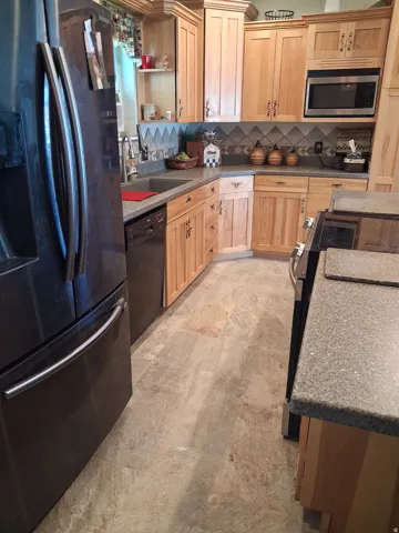 Light wood-finish cabinetry, stainless steel appliances, durable countertop surfaces, and patterned tile backsplash