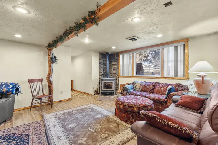 Living area with a wood stove, wood finished floors, a textured ceiling, and recessed lighting