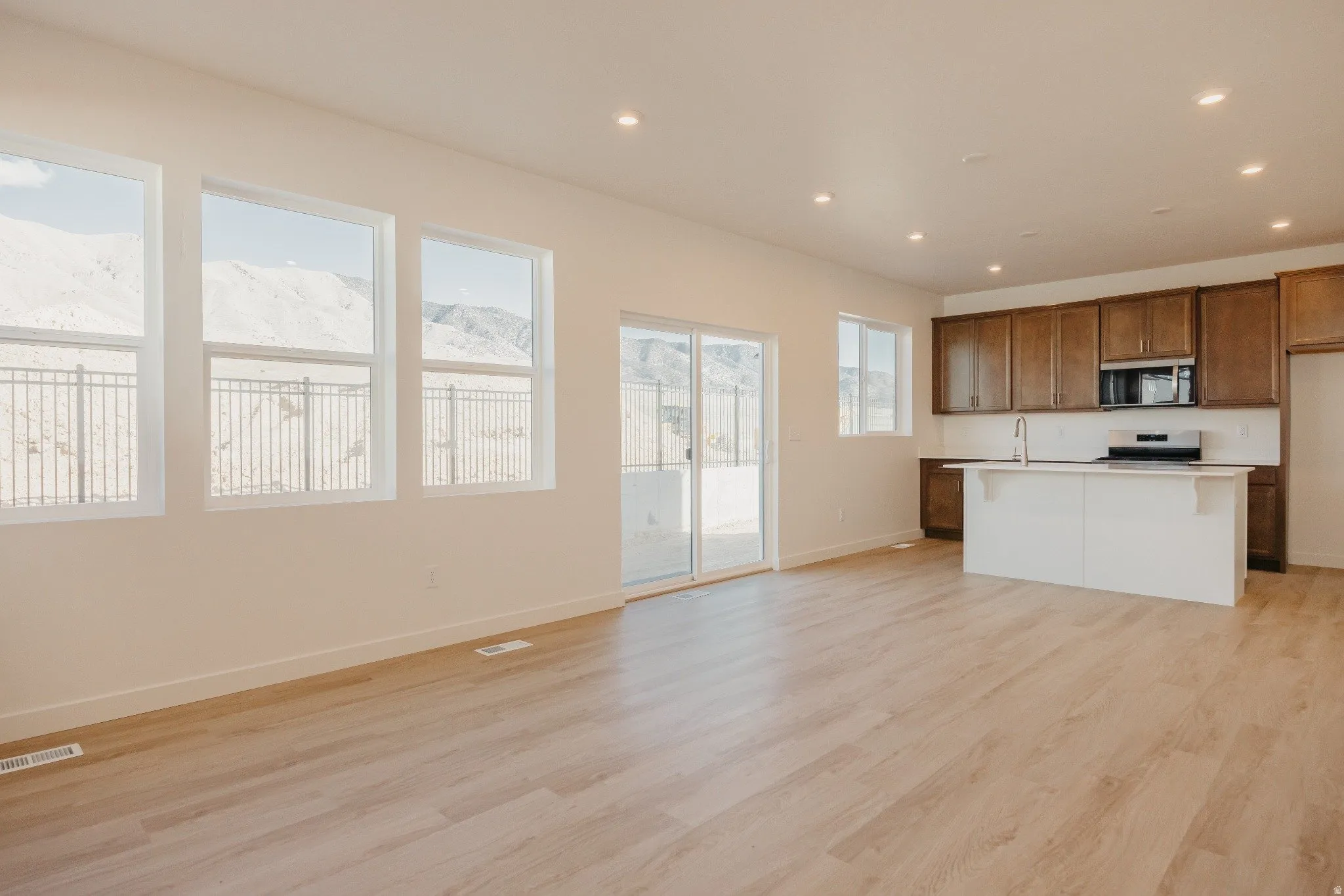 Kitchen with open floor plan, light countertops, a mountain view, light wood finished floors, and a kitchen island with sink