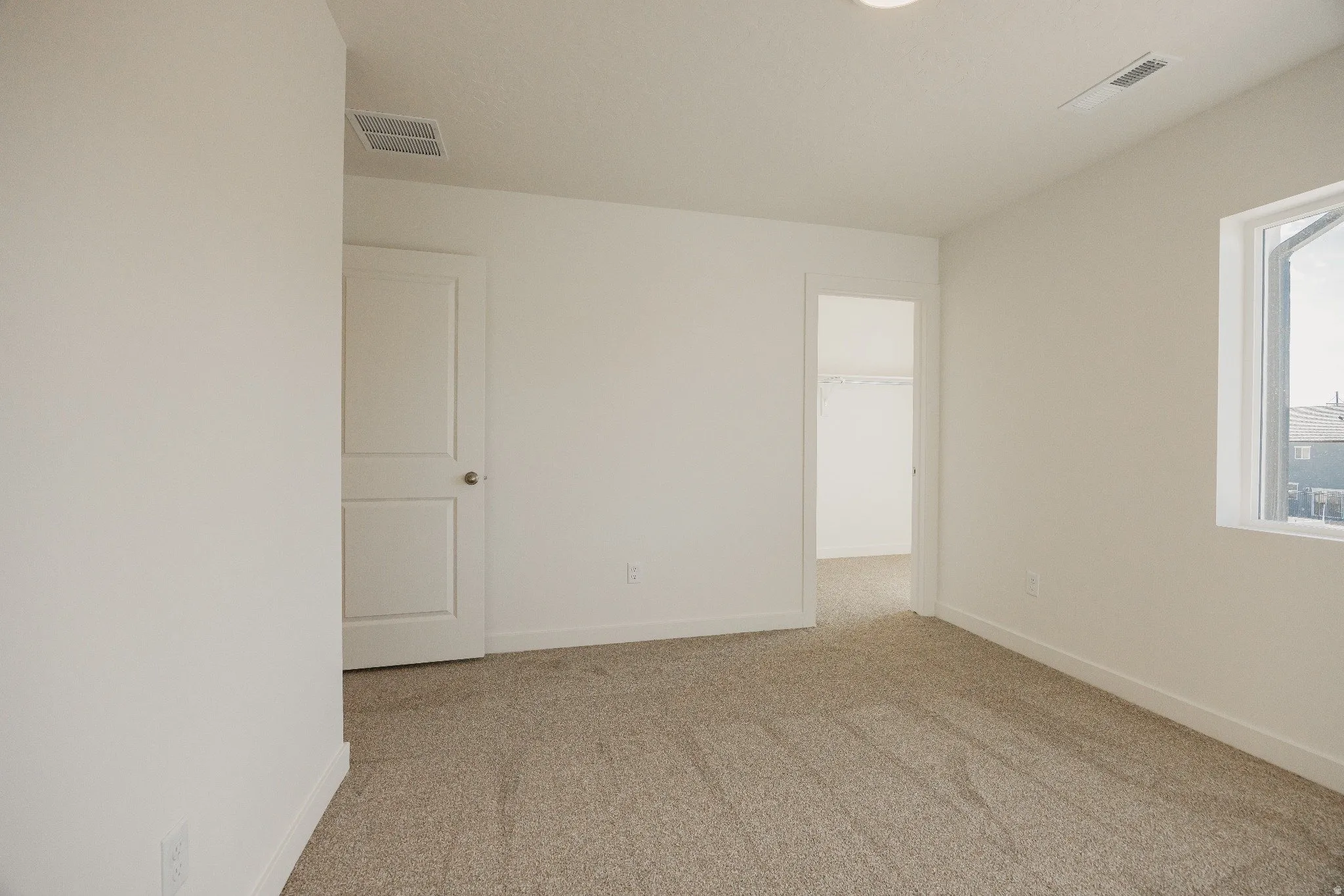 Unfurnished room featuring light carpet and baseboards