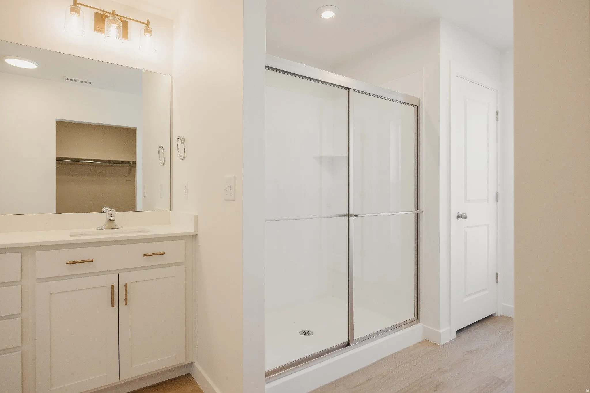 Bathroom with vanity, a stall shower, light wood-type flooring, and recessed lighting
