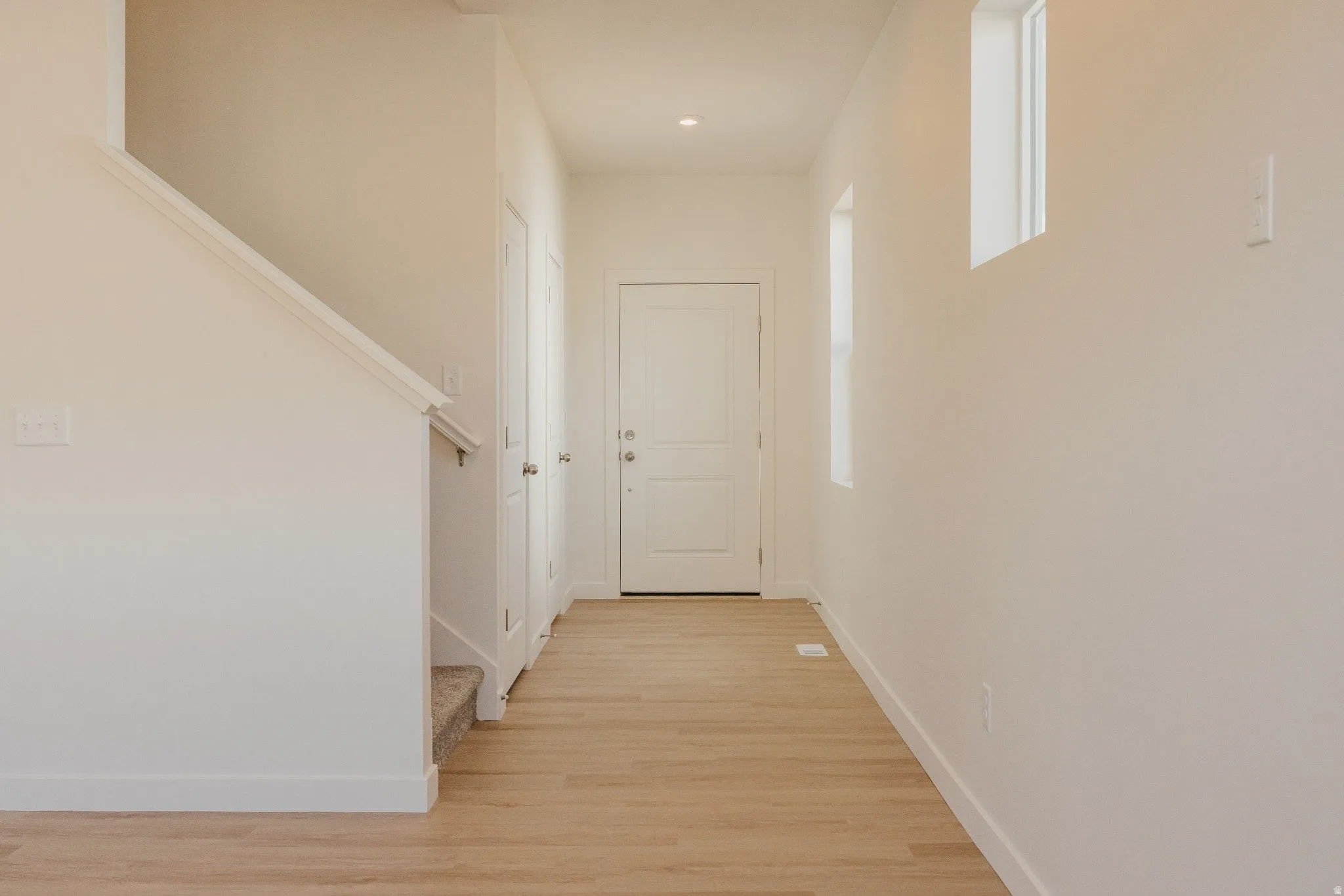 Hallway with stairway and light wood-style floors