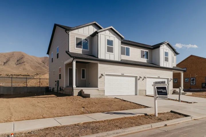 View of front of home featuring board and batten siding, a garage, concrete driveway, covered porch, and a mountain view
