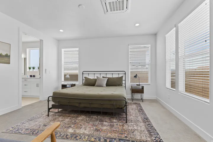 Bedroom with light colored carpet, cooling unit, connected bathroom, and recessed lighting