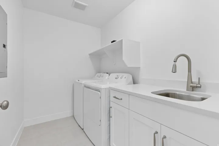 Washroom featuring separate washer and dryer, electric panel, and cabinet space