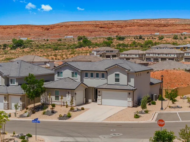 View of front of home with driveway, stucco siding, a residential view, stone siding, and a garage
