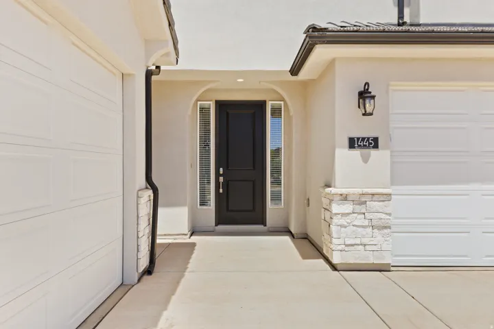 Property entrance featuring a garage, stucco siding, and stone siding