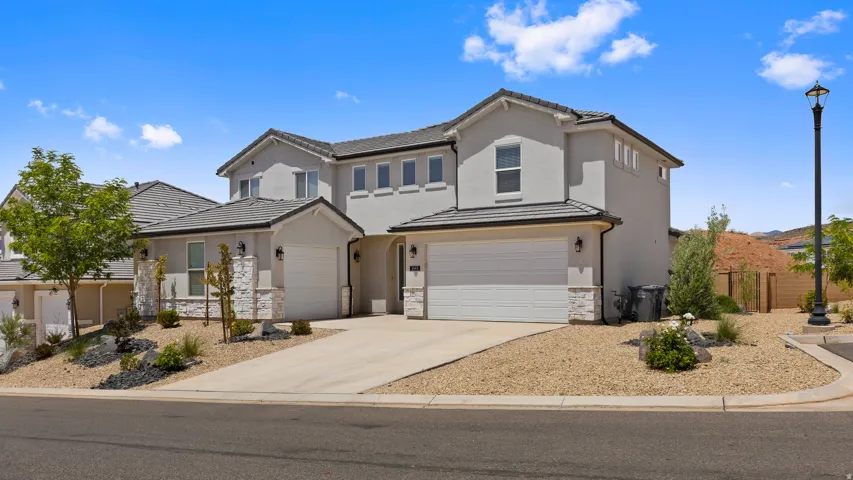 Traditional home with concrete driveway, stucco siding, stone siding, a tile roof, and a garage