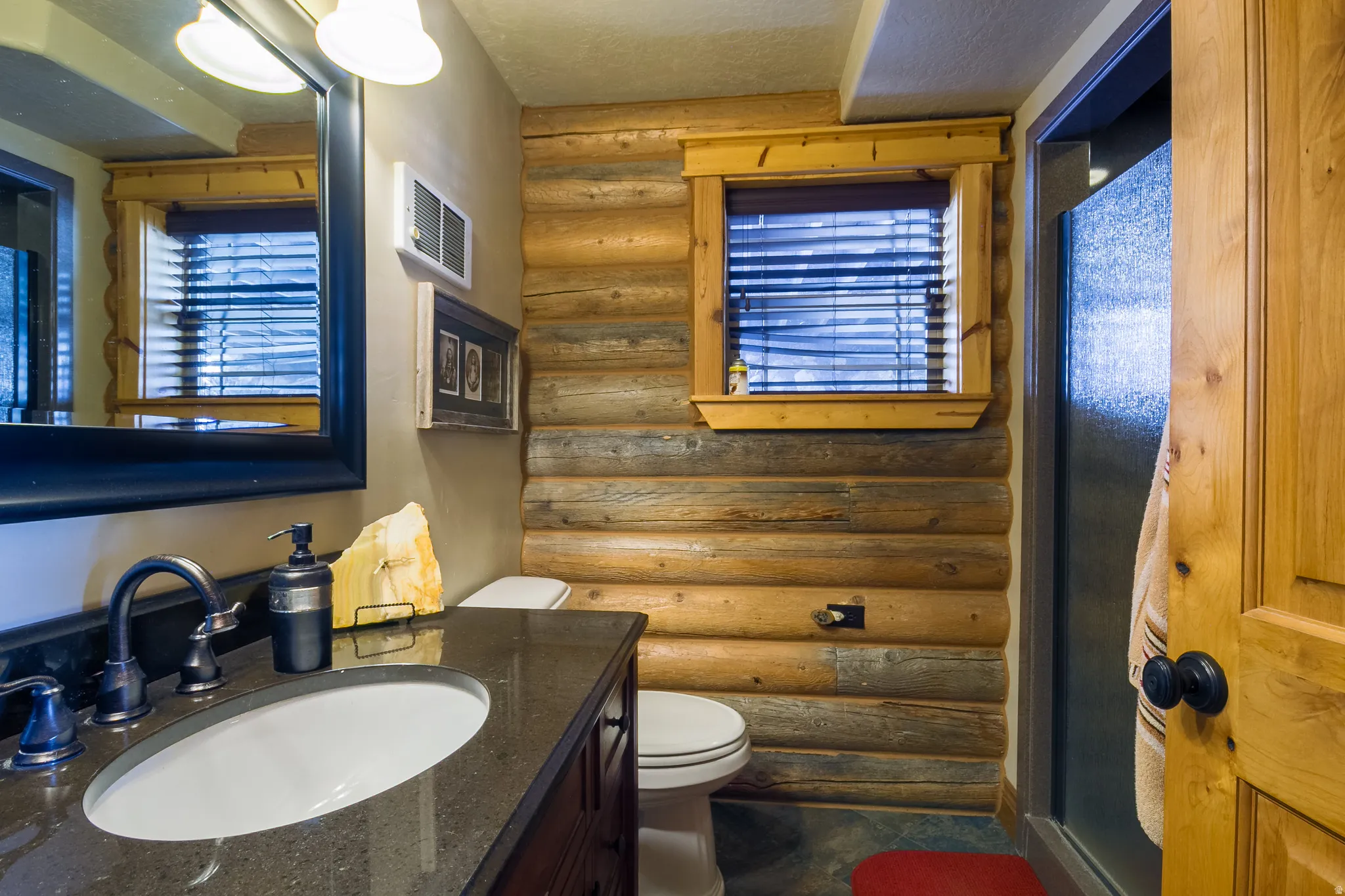 Bathroom featuring log walls, vanity, and a textured ceiling