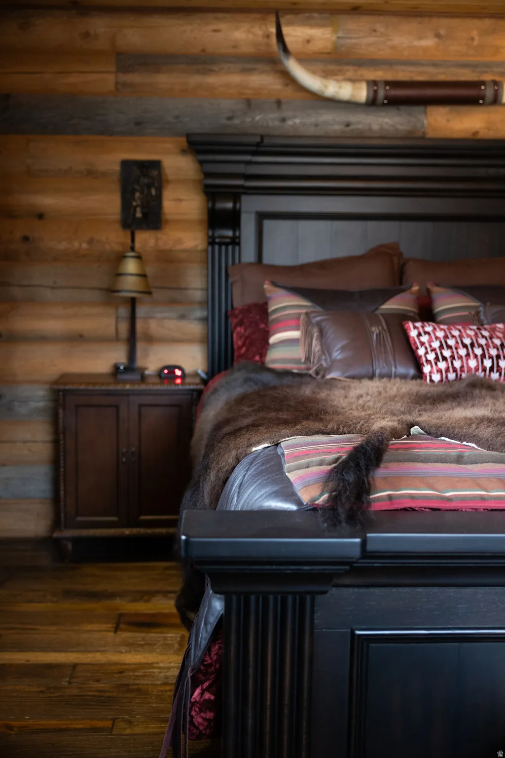 Bedroom with log walls and dark wood-style flooring
