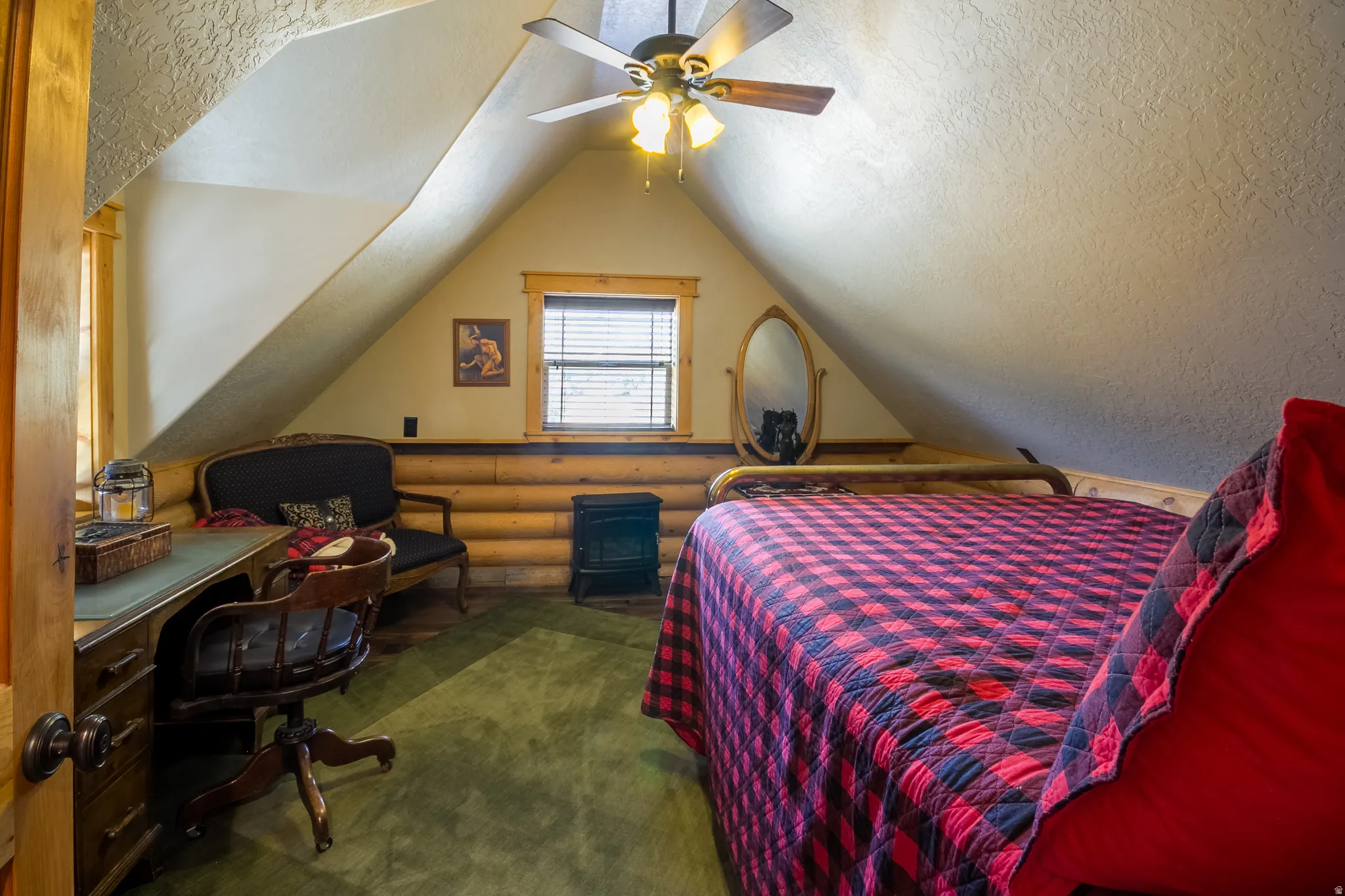 Bedroom with vaulted ceiling, an office area, a textured ceiling, ceiling fan, and rustic walls