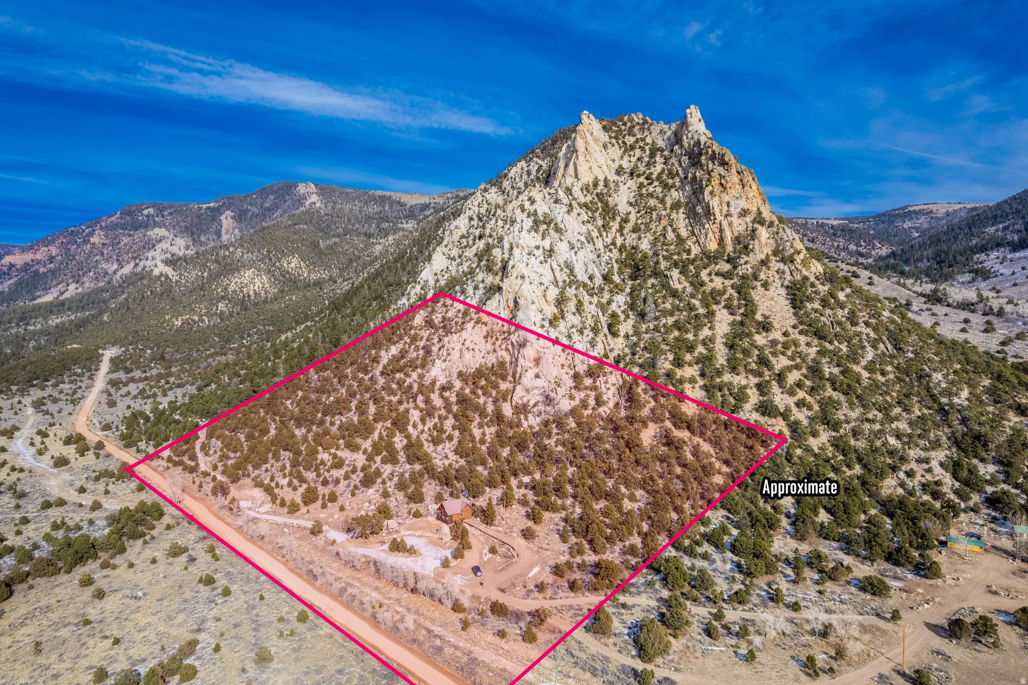 Aerial view of sparsely populated area with property parcel outlined and a mountainous background
