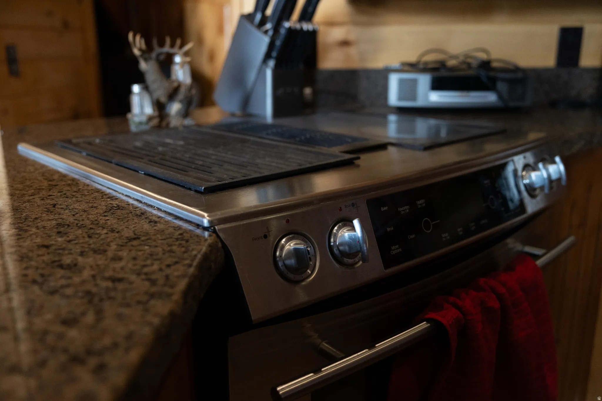 Kitchen view of stainless steel range with electric cooktop and dark stone counters