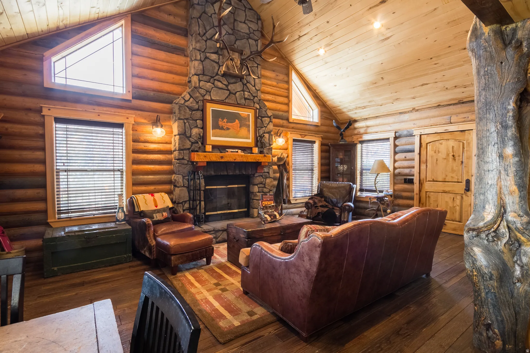 Living area featuring high vaulted ceiling, a fireplace, dark wood-type flooring, wooden ceiling, and log walls