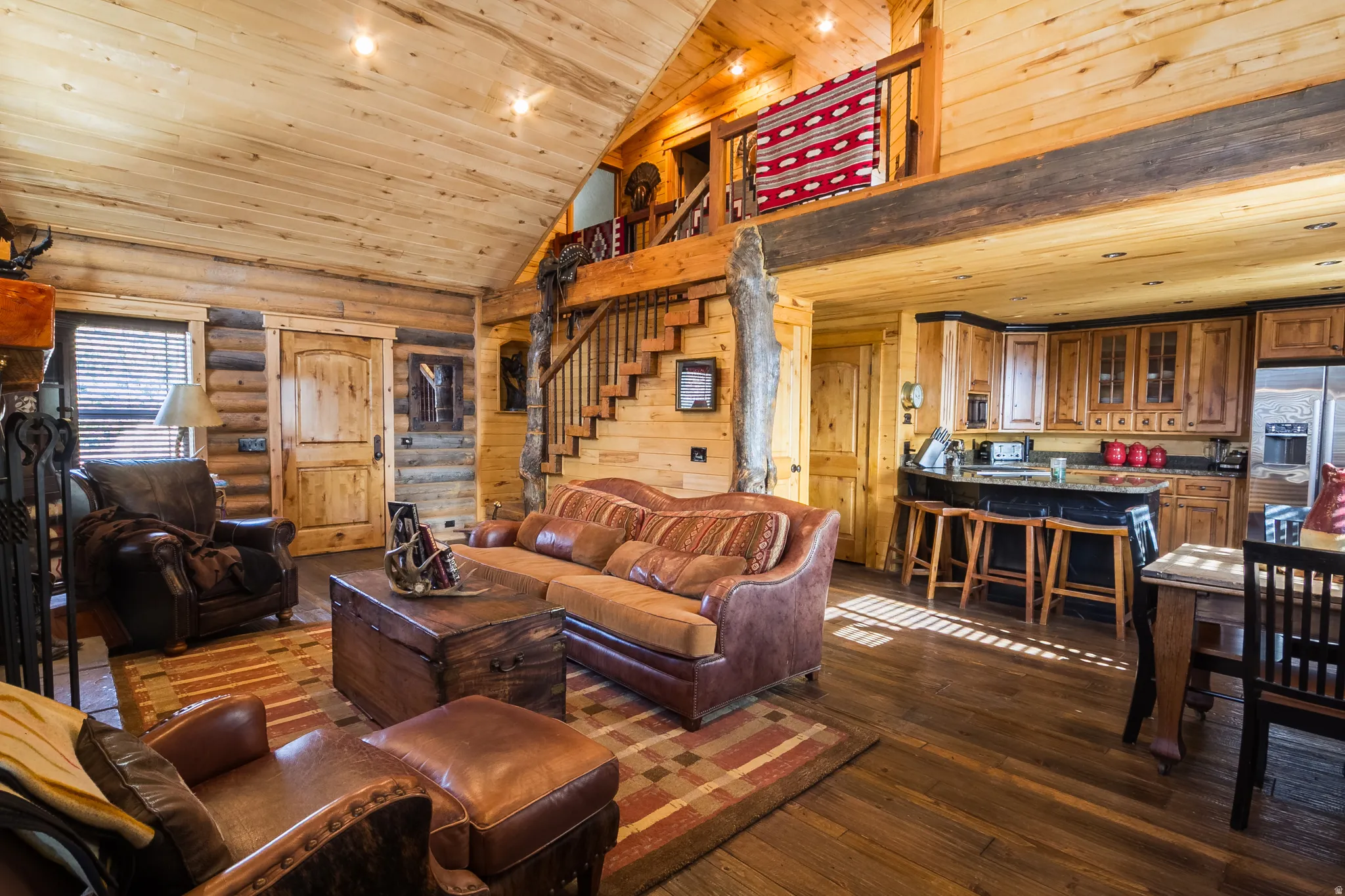Living room with stairs, dark wood finished floors, high vaulted ceiling, wooden ceiling, and rustic walls